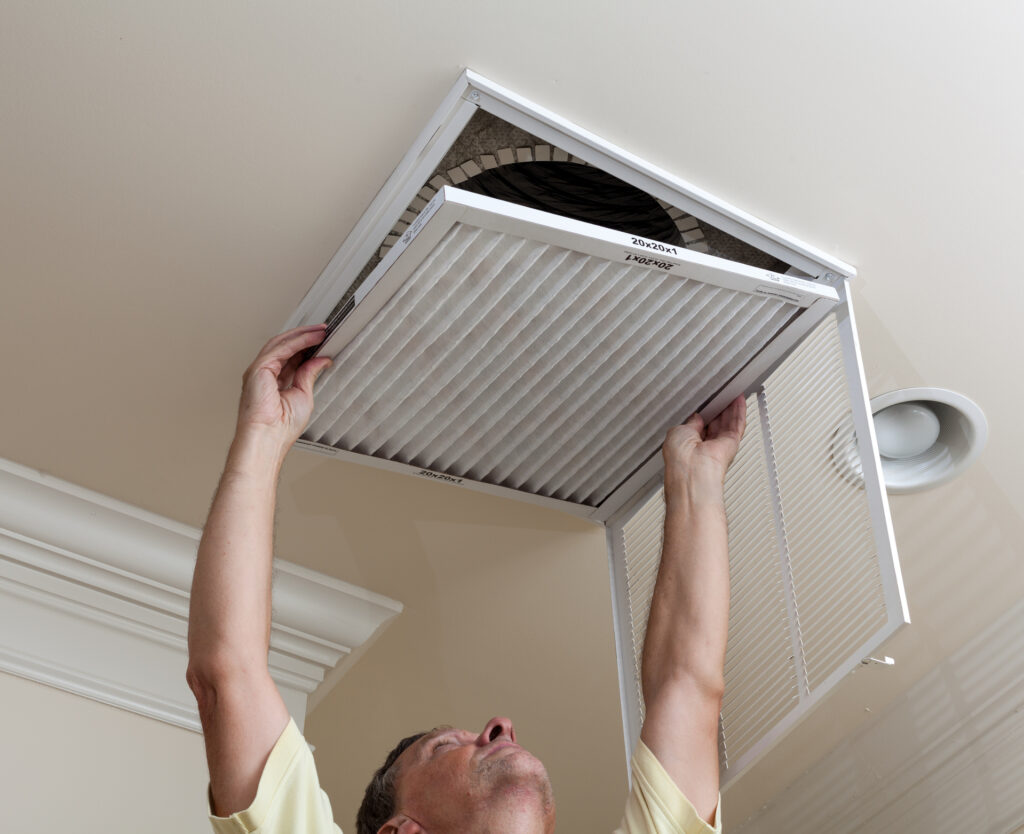 Senior man opening air conditioning filter in ceiling